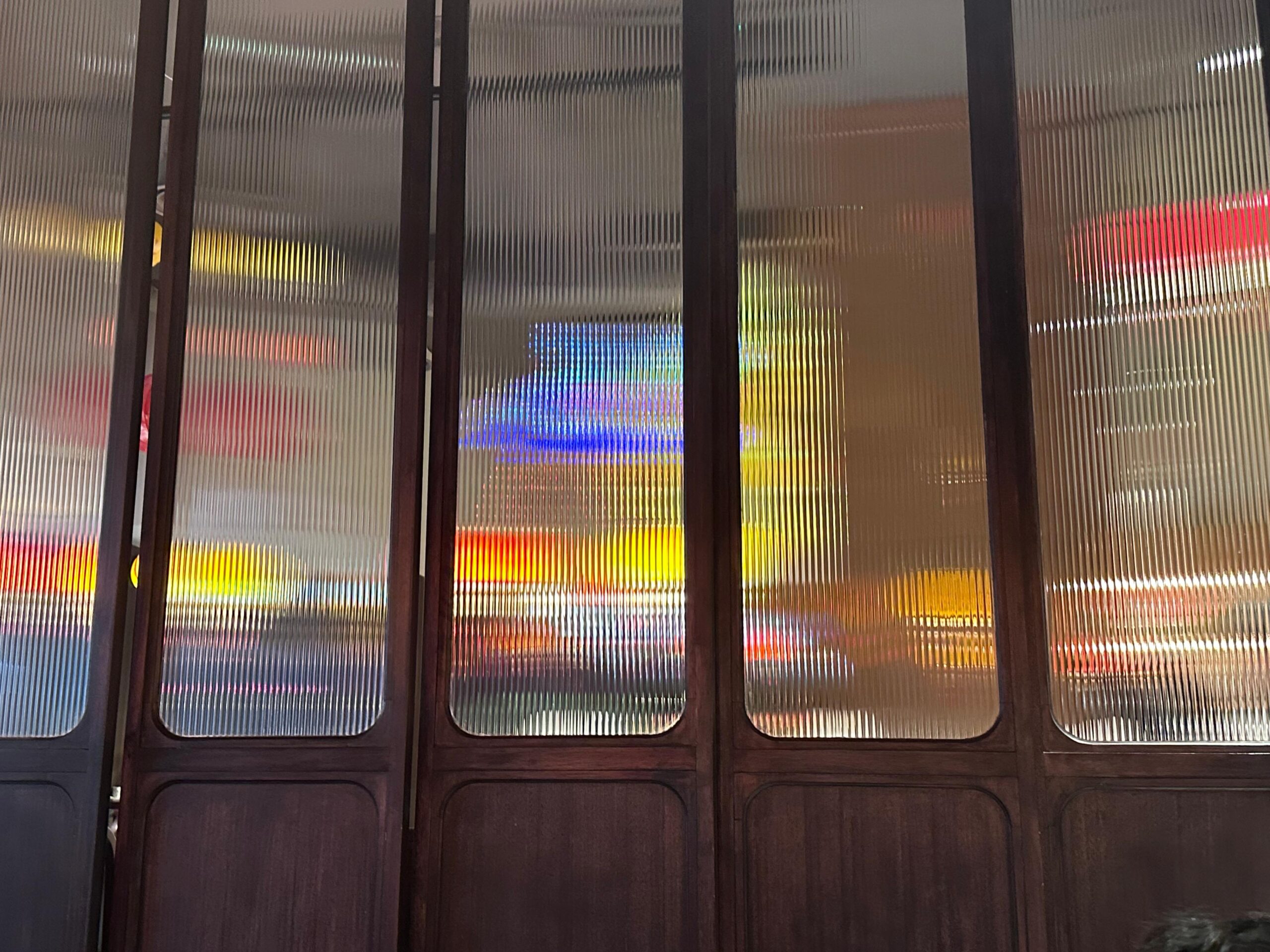 Fluted glass panels with vertical ribbed texture diffusing city lights into soft, linear patterns, capturing the play of light and movement that inspires the Fluted Light rug.​