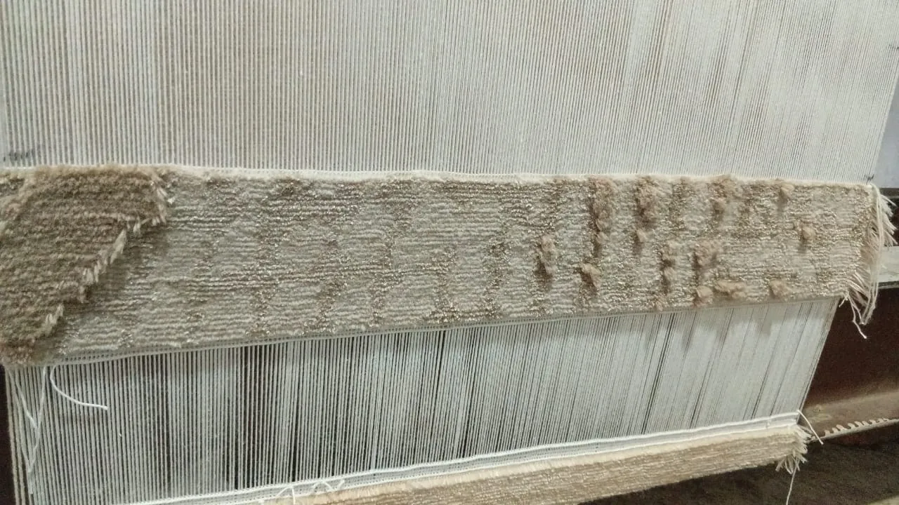 Close-up of hand-knotted rug in progress on the loom, showing varying pile heights and tonal texture created through New Zealand wool and silk, highlighting Northwest 35 craftsmanship.​